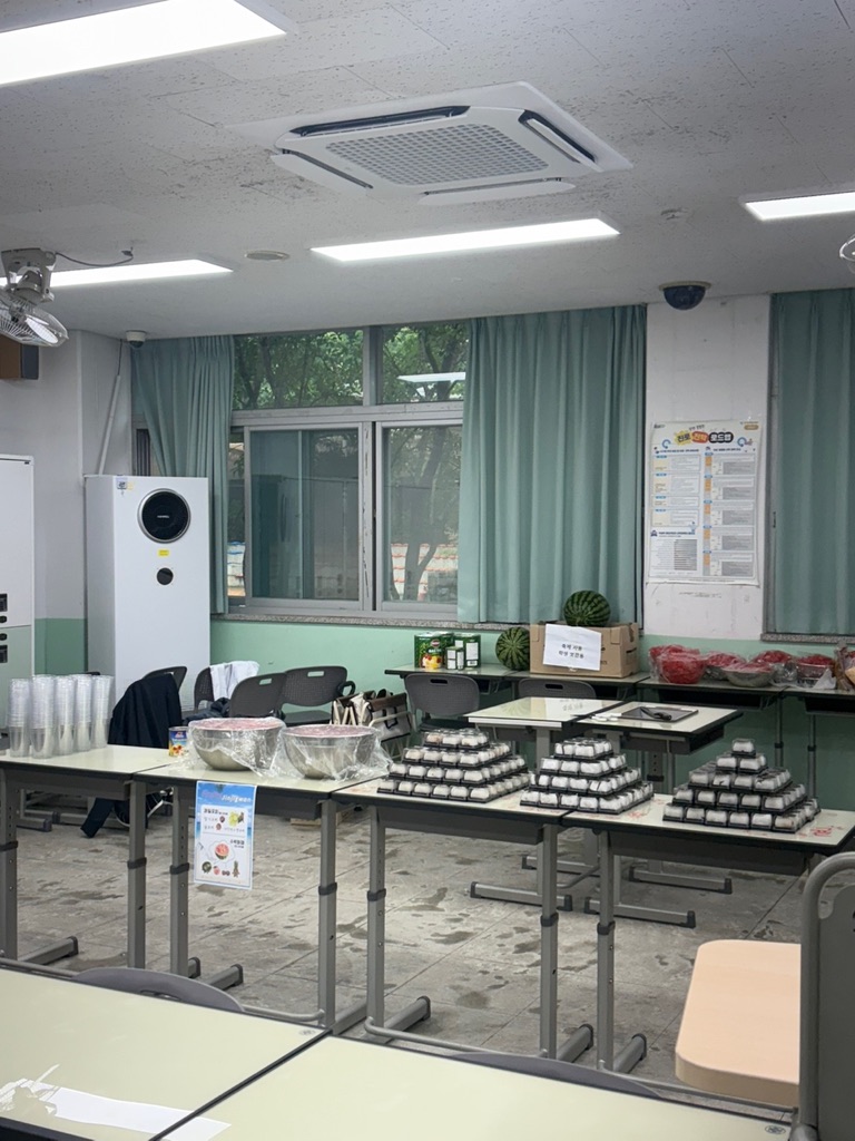 Jinjigwan bake sale setup with tiered dessert displays in a classroom